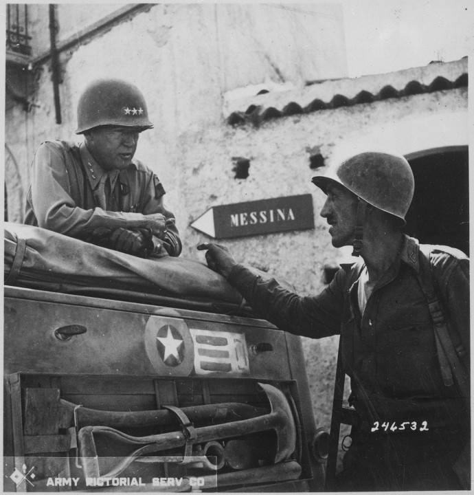 Le lieutenant-colonel Lyle W. Bernard, commandant le 2e bataillon du 30e régiment d'infanterie, en conversation avec le lieutenant-général George S. Patton, commandant la septième armée américaine, près de Brolo, en Sicile, juillet 1943.